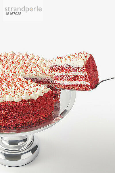Stück frischer roter Samtkuchen auf Kuchenschaufel vor weißem Hintergrund
