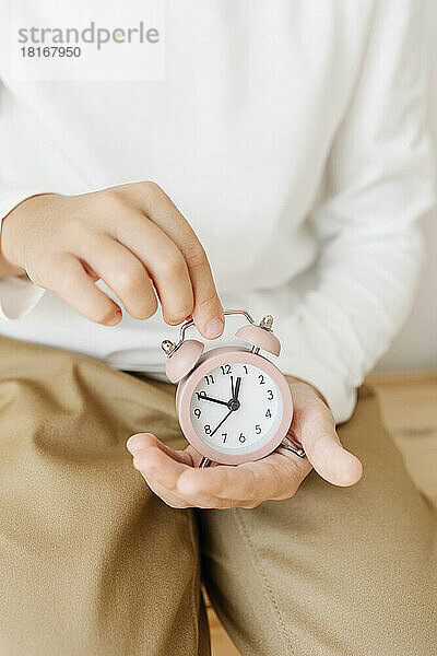 Hands of girl holding pink alarm clock