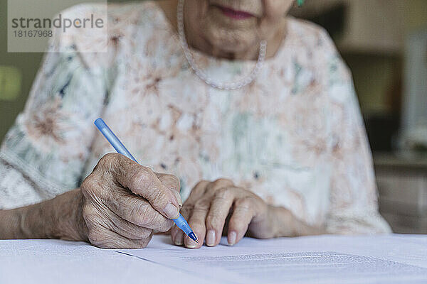 Ältere Frau unterzeichnet Vertragspapiere auf dem Tisch