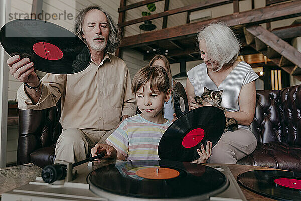 Enkelin wechselt mit den Großeltern zu Hause die Schallplatte am Plattenspieler