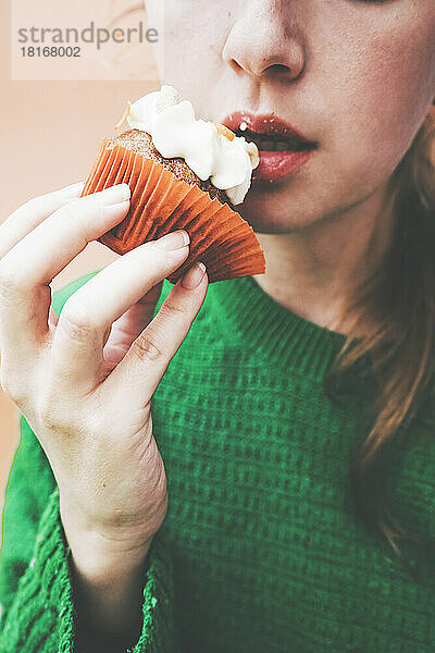 Frau isst Cupcake mit Zuckerguss