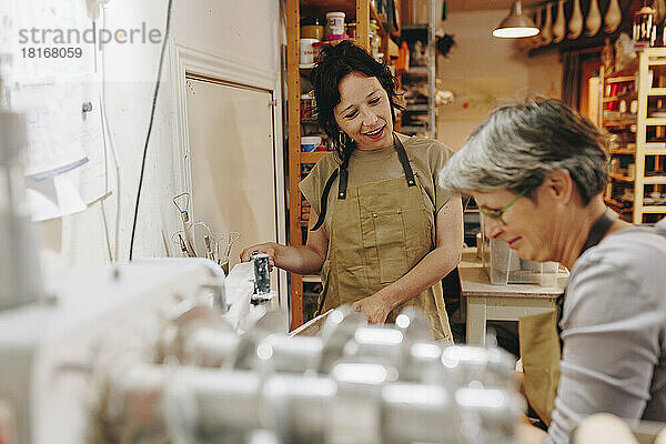 Lächelnder Unternehmer im Gespräch mit Kollegen  der in der Keramikwerkstatt arbeitet