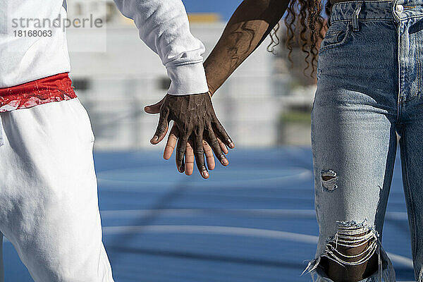 Mann hält Frau an der Hand am Sportplatz
