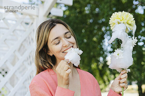 Glückliche Frau  die Zuckerwatte mit Blume isst