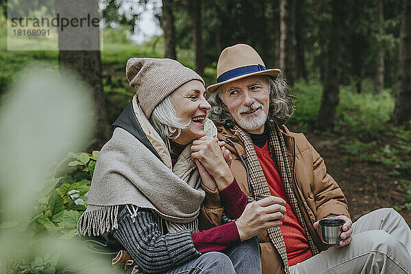Lächelnde reife Frau mit älterem Mann  der im Wald sitzt