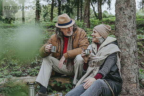 Glückliches Paar genießt heißen Tee im Wald