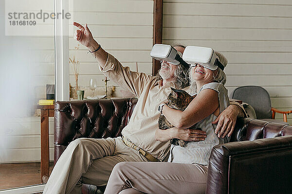 Älterer Mann und Frau mit VR-Brille sitzen zu Hause auf dem Sofa