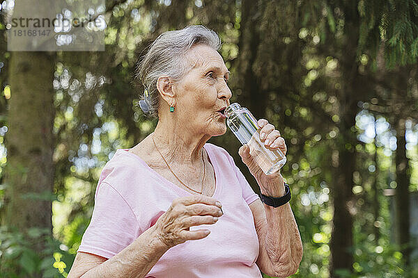 Ältere Frau trinkt Wasser aus der Flasche im Park