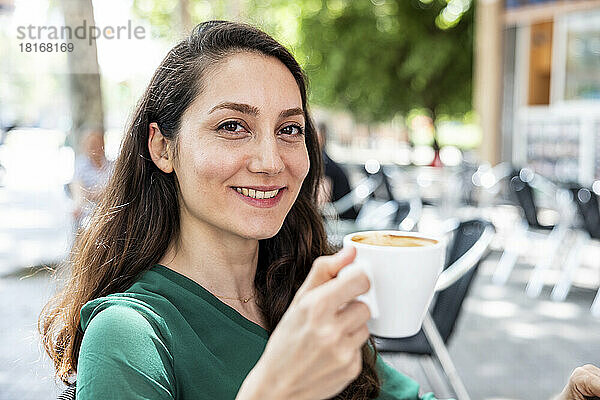 Glücklicher Freiberufler mit Kaffeetasse im Straßencafé