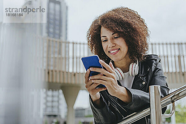 Lächelnde junge Frau  die mit dem Smartphone im Internet surft