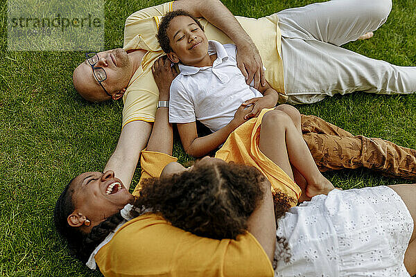 Glückliche Frau mit Mann und Kindern  die auf Gras liegen