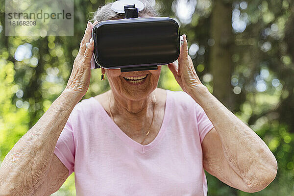 Lächelnde ältere Frau  die einen Virtual-Reality-Simulator trägt