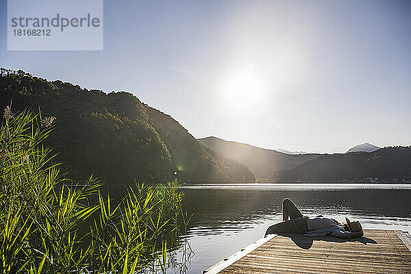 Reife Frau ruht sich im Urlaub auf einem Steg über dem See aus