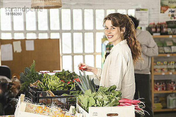 Lächelnde Frau kauft Gemüse im Gemüseladen