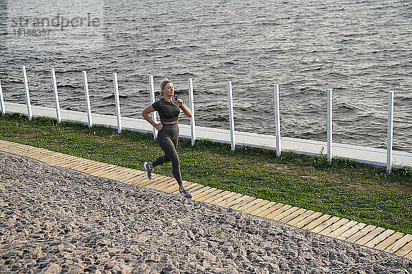 Mature woman jogging on footpath by sea