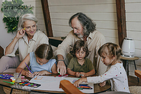 Großeltern helfen Kindern beim Malen zu Hause
