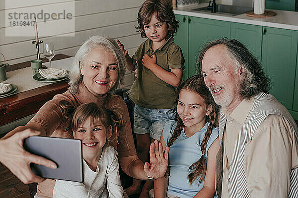 Großmutter mit Enkelkindern macht zu Hause ein Selfie per Tablet-PC