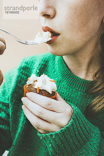 Frau isst Zuckerguss auf Cupcake mit Gabel