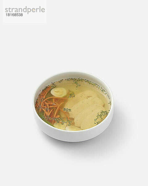 Fresh chicken soup with egg and vegetables in bowl on white background