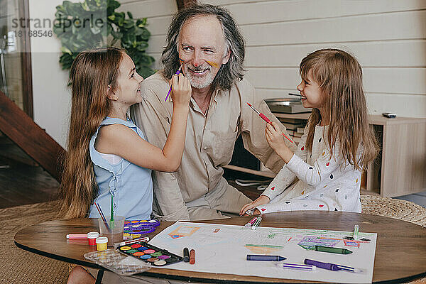 Enkelinnen haben Spaß daran  zu Hause das Gesicht des Großvaters zu malen