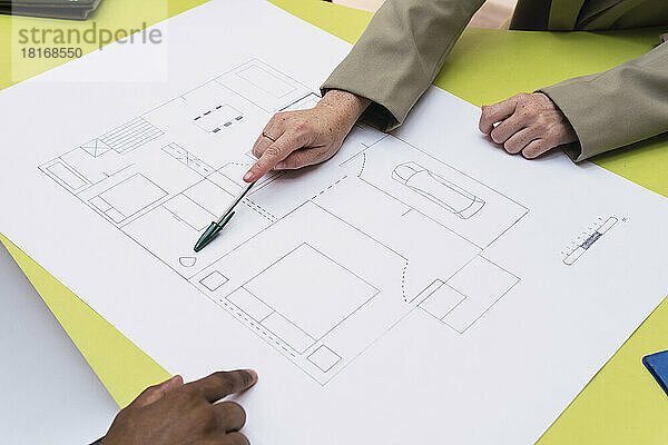 Architekt erklärt Grundriss auf Tisch