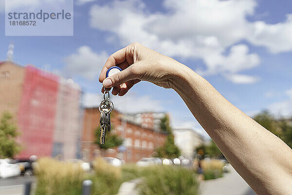 Hand einer Frau  die an einem sonnigen Tag Schlüssel zeigt