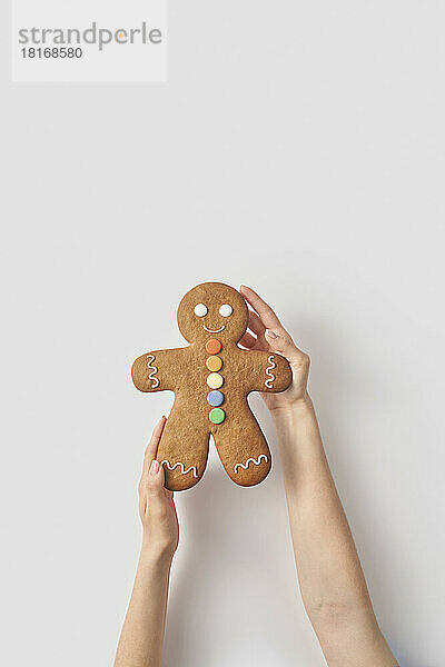 Woman holding gingerbread man cookie on white background