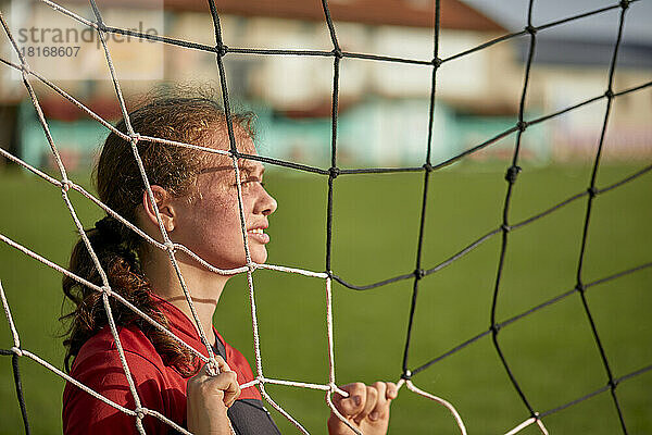 Mädchen steht an sonnigen Tagen hinter dem Netz auf dem Feld