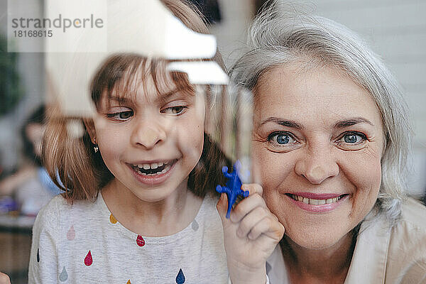 Lächelnde Großmutter mit Enkelin durch Fenster gesehen