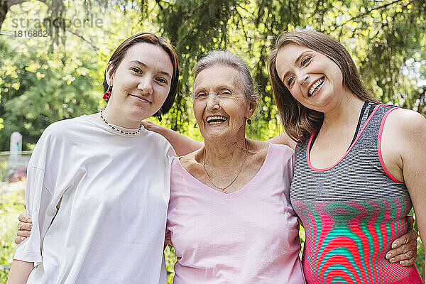 Fröhliche Seniorin mit Tochter und Enkelin steht im Park