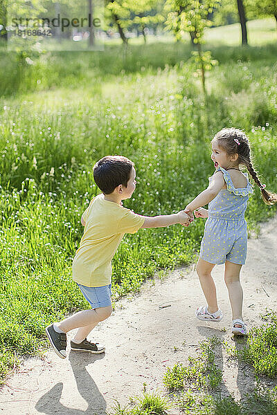 Glückliche Geschwister  die an einem sonnigen Tag gemeinsam im Park spielen