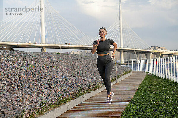 Lächelnde Frau joggt auf Fußweg
