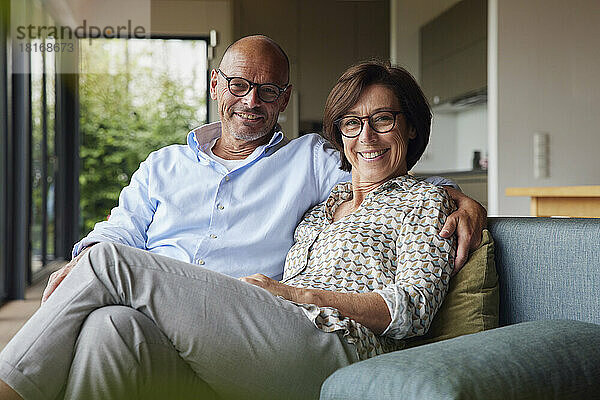 Happy senior couple wearing eyeglasses sitting together at home