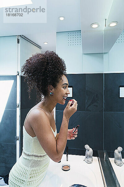 Frau trägt zu Hause im Badezimmer Lippenstift auf