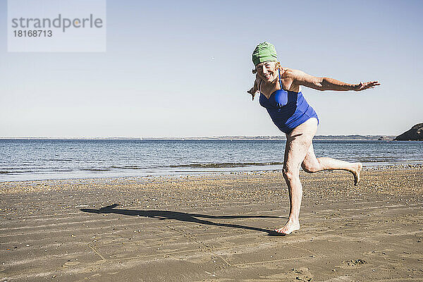 Frau hat Spaß beim Laufen am Strand an einem sonnigen Tag