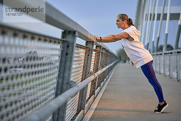 Frau trainiert in der Nähe des Geländers auf der Brücke