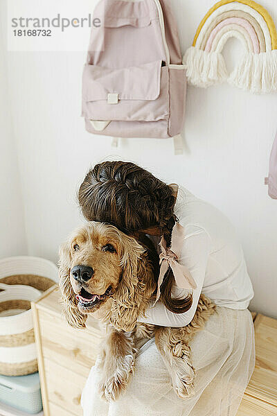 Mädchen umarmt Hund  der auf Schrank sitzt