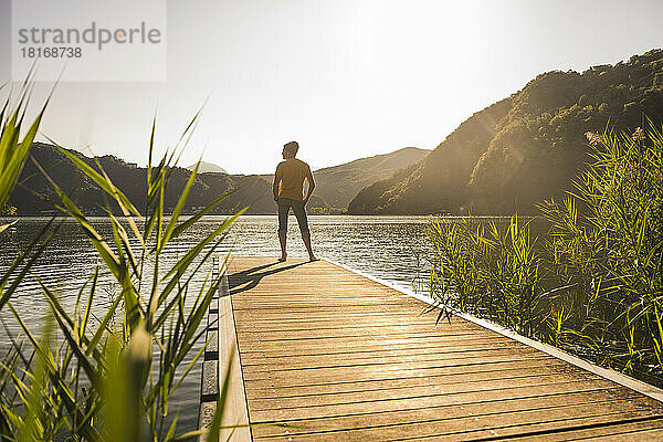 Man standing on jetty over lake by mountains at vacation