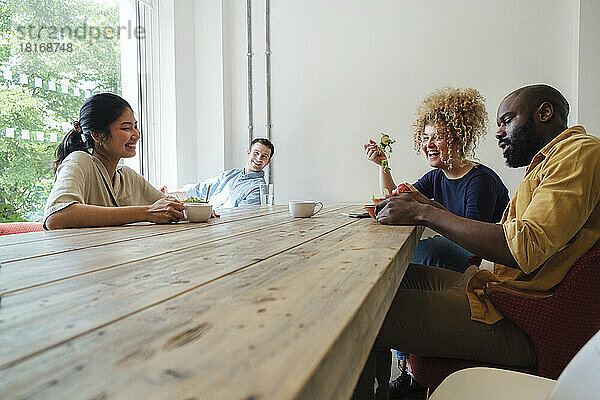 Geschäftsleute essen gemeinsam im Lehrerzimmer eines modernen Büros gesund zu Mittag