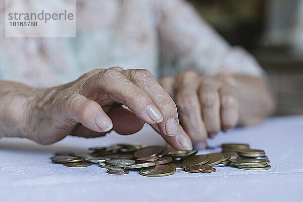 Hände einer älteren Frau  die zu Hause Münzen zählt