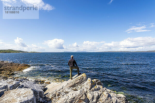 Mann steht auf einem Felsen am Loch Ailort See