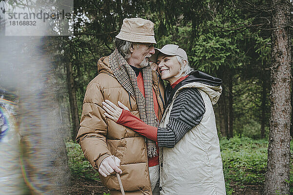 Smiling mature woman embracing man in forest