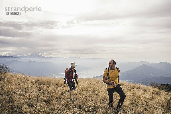 Glückliches älteres Paar wandert auf einem Berg unter bewölktem Himmel