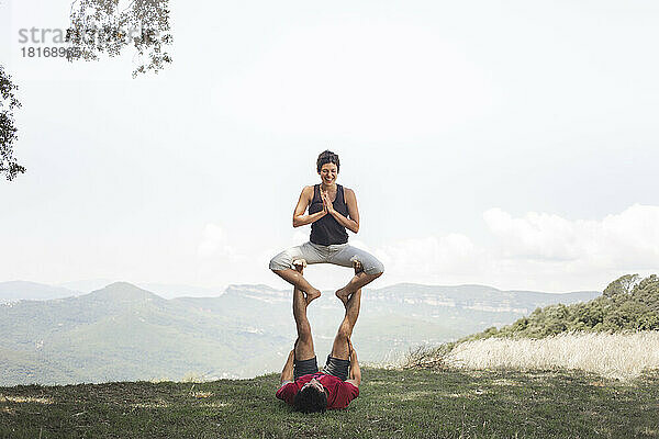 Man and woman practicing acroyoga on top of mountain