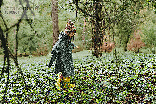 Mädchen trägt übergroßen Pullover und geht im Wald spazieren
