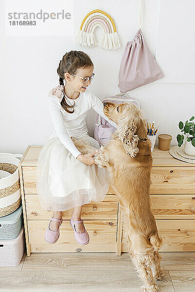 Lächelndes Mädchen  das zu Hause mit Hund spielt