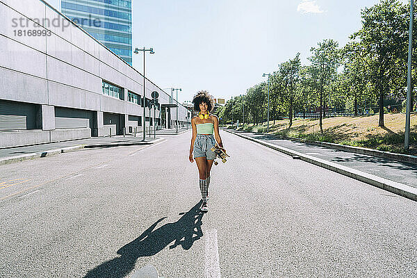 Frau mit Skateboard läuft auf der Straße