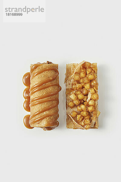 Stuffed sweet apple and caramel crepe rolls against white background