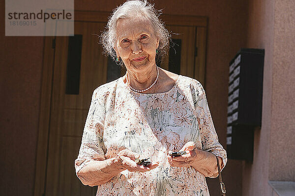 Ältere Frau mit Autoschlüsseln an sonnigem Tag