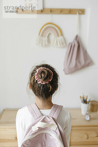 Rückansicht eines Mädchens mit rosa Rucksack und Haarknoten